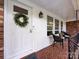 Close up of the charming front porch with chairs and wreath on the front door at 6616 Williams Rd, Charlotte, NC 28215