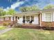 Inviting front porch with brick flooring, chairs, and manicured lawn at 6616 Williams Rd, Charlotte, NC 28215