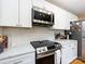 Bright kitchen features white cabinets, subway tile backsplash, and stainless steel microwave and range at 6616 Williams Rd, Charlotte, NC 28215