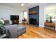 Living room featuring a painted brick fireplace, hardwood floors, and a TV at 6616 Williams Rd, Charlotte, NC 28215