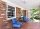 Cozy front porch with brick flooring and walls, comfortable seating, and plenty of natural light at 6616 Williams Rd, Charlotte, NC 28215