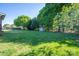 Large, grassy backyard featuring mature trees and a storage shed, perfect for outdoor activities at 695 Linwood Rd, Mooresville, NC 28115