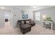 Relaxing bonus room featuring a cozy brown couch, white desk, and natural light from the window at 1062 River Haven Sw Ave, Concord, NC 28025
