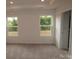 Bright bedroom featuring two windows and neutral-toned carpet at 1119 Overbrook Pl, Wingate, NC 28174