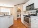 Cozy kitchen featuring white cabinets, stainless steel appliances, and a laundry room entrance at 113 Rocky Trail Ct, Fort Mill, SC 29715