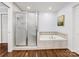 Well-maintained bathroom features a tub, tiled walls, hardwood floors, and a glass-enclosed shower at 1209 Yale Pl, Charlotte, NC 28209