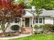 Inviting front entrance with brick steps, lush landscaping, and a classic white brick facade at 1209 Yale Pl, Charlotte, NC 28209