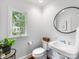 Bright powder room with a pedestal sink, natural light, and a decorative mirror at 1209 Yale Pl, Charlotte, NC 28209