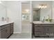 Dual sink bathroom with gray cabinets, quartz countertops, decorative mirrors, and tiled shower with glass door at 131 Berkeley Ave # D, Mooresville, NC 28117