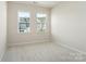Cozy bedroom with two windows showcasing neighborhood views and neutral carpeting at 131 Berkeley Ave # D, Mooresville, NC 28117