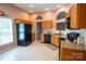 Bright kitchen with warm wood cabinets, neutral countertops, and black appliances at 134 Walmsley Pl, Mooresville, NC 28117
