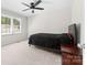 Bedroom featuring a black tufted bed, ceiling fan, and window with natural light at 14812 Stonegreen Ln, Huntersville, NC 28078