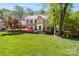 Charming two-story brick home featuring a lush, landscaped front yard with colorful flower beds at 14812 Stonegreen Ln, Huntersville, NC 28078