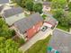 Aerial view of a charming red house with an adjacent garage, and a well-maintained putting green at 1508 Peaceful Way Dr, Charlotte, NC 28206