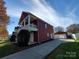 Side view of a two-story house featuring red siding, white trim, detached garage, and well-kept landscaping at 1508 Peaceful Way Dr, Charlotte, NC 28206