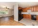 View of kitchen with wood cabinets, black appliances, and neutral-toned flooring, open to living area at 1532 Downs Ave, Charlotte, NC 28205