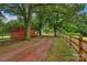 A scenic driveway leads to a beautiful property, lined with mature trees and a wooden fence at 1607 Old Lawyers Rd, Marshville, NC 28103