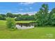 Aerial view of a serene pond surrounded by vibrant green grass and mature trees at 1607 Old Lawyers Rd, Marshville, NC 28103