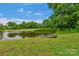 Picturesque pond with a canoe resting on the grassy bank under a clear, blue sky at 1607 Old Lawyers Rd, Marshville, NC 28103