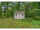 Charming backyard shed with a grey exterior surrounded by lush greenery and a wooden fence at 1607 Old Lawyers Rd, Marshville, NC 28103