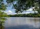 Picturesque lake view featuring lush green trees against a bright blue sky with scattered clouds at 170 Atwater Landing Dr, Mooresville, NC 28117