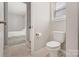 Neutral colored bathroom with a toilet, window, and a view into the bedroom with carpet flooring at 190 Tetcott St, Mooresville, NC 28115