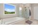 Bright bathroom featuring a soaking tub under a window and a glass-enclosed shower with beige tiling at 190 Tetcott St, Mooresville, NC 28115