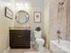 Bathroom featuring dark cabinets, a round mirror, and a shower-tub combination at 2119 Augusta National Dr, Denver, NC 28037
