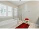 Bright bathroom featuring a glass-enclosed shower, soaking tub, and large window at 2119 Augusta National Dr, Denver, NC 28037