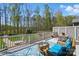 Relaxing outdoor deck with beautiful wooded view, wicker furniture, and decorative blue area rug at 2119 Augusta National Dr, Denver, NC 28037