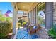Inviting porch with brick columns and wicker chairs on a blue patterned rug and colorful flowers at 2119 Augusta National Dr, Denver, NC 28037