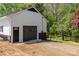 Detached garage with a dark garage door and matching service door, set among lush greenery at 221 Belton Ave, Mount Holly, NC 28120