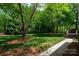Lush backyard with manicured lawn, mature trees, and a walkway leading to a deck at 2382 Erika Ln, Gastonia, NC 28056