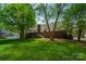 Expansive backyard with lush green grass, mature trees, and a glimpse of the brick home at 2382 Erika Ln, Gastonia, NC 28056