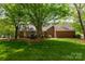 Lush, grassy backyard framed by mature trees and the brick exterior of the home at 2382 Erika Ln, Gastonia, NC 28056