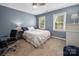 Blue bedroom features two windows, a ceiling fan, a desk, and an upholstered chair, creating a relaxing atmosphere at 2382 Erika Ln, Gastonia, NC 28056