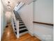 Hallway with stairs featuring neutral walls, hardwood floors and a classic chandelier at 2400 Commonwealth Ave, Charlotte, NC 28205
