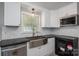 Well-lit kitchen boasts white cabinetry, stainless steel sink, modern appliances, and sleek backsplash at 2439 Caswell Ct, Gastonia, NC 28054