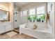 Bright bathroom featuring a soaking tub, a glass shower, and natural light from the windows at 288 Ridge Reserve Dr, Lake Wylie, SC 29710