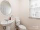 Cozy half bathroom with pedestal sink, toilet, mirror and a bright window at 3005 Sandbox Cir, Indian Trail, NC 28079