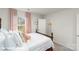Bright bedroom showcasing a spindle bed frame, white linens, and window with pink curtains at 3912 Coleman Dr, Charlotte, NC 28215