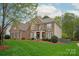 Stunning brick home featuring a lush lawn, mature trees, and manicured landscaping at 4027 Wallbrook Dr, Matthews, NC 28105