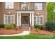 Charming front porch with brick steps, white columns, and decorative wreaths on double front doors at 4027 Wallbrook Dr, Matthews, NC 28105