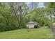 View of the backyard showing a lush green lawn and mature trees with a small building in the background at 500 3Rd St, Stanley, NC 28164