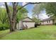 The green backyard features a detached building, a neighboring home, and a lush tree providing shade at 500 3Rd St, Stanley, NC 28164
