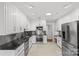 Modern kitchen with stainless steel appliances, black countertops, and custom white cabinets at 5306 Sandtrap Ln, Charlotte, NC 28226