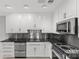 Kitchen featuring stainless steel appliances, black counters, white cabinets, and tile flooring at 5306 Sandtrap Ln, Charlotte, NC 28226