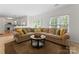 Inviting living room features a large sectional sofa, neutral tones, and a view to the kitchen and out to the back yard at 6101 Park Hill Rd, Charlotte, NC 28277