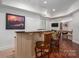 Finished basement bar area with stools, granite counter and wood flooring at 7912 Baltusrol Ln, Charlotte, NC 28210