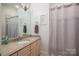 Bright bathroom featuring a beige vanity with granite top, framed mirror, and lavender-themed decor at 7912 Baltusrol Ln, Charlotte, NC 28210